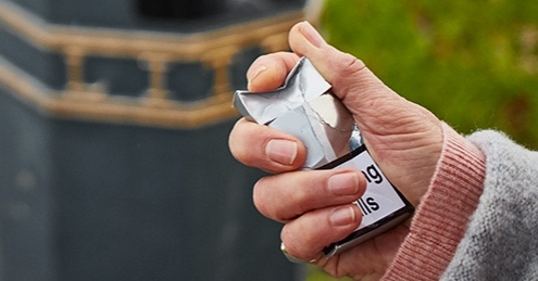 Hand crushing a packet of cigarettes